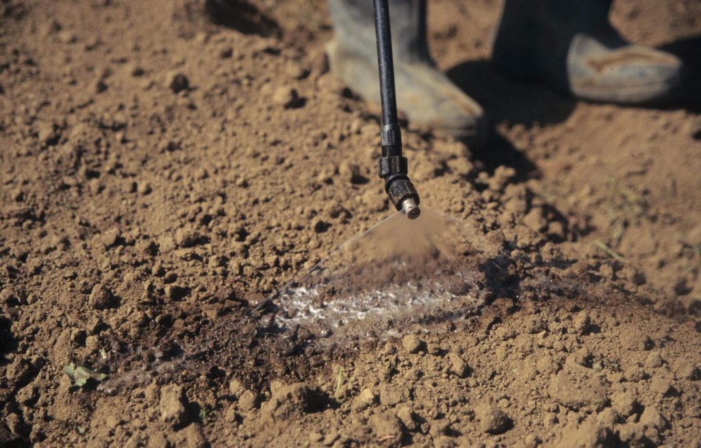 Close-up of a nozzle spraying a product on the soil surface